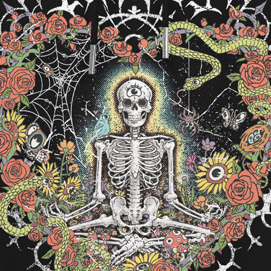 Detail of a black hoodie with vibrant digital artwork of a meditating skeleton in a yoga pose amid colorful flowers and insects. A bluebird sits on the skeleton's shoulder. It's framed by a heart-shaped iron fence with snakes, roses, and gothic 'Manifest' text. Expressive eyes and a third eye symbolize spiritual awakening. Despite the edgy look, it carries an uplifting message of manifestation and abundance. © Donny Meloche, 2023.