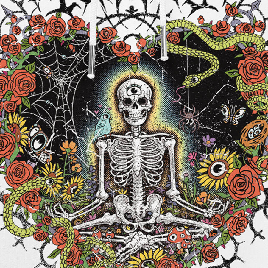 Detail of a white hoodie with vibrant digital artwork of a meditating skeleton in a yoga pose amid colorful flowers and insects. A bluebird sits on the skeleton's shoulder. It's framed by a heart-shaped iron fence with snakes, roses, and gothic 'Manifest' text. Expressive eyes and a third eye symbolize spiritual awakening. Despite the edgy look, it carries an uplifting message of manifestation and abundance. © Donny Meloche, 2023.