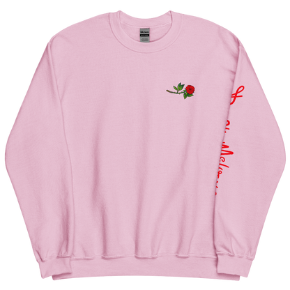 The front of a pink sweatshirt with a small illustration of a tilted red rose; placed over the heart on the left side of the chest. © Donny Meloche, 2023.